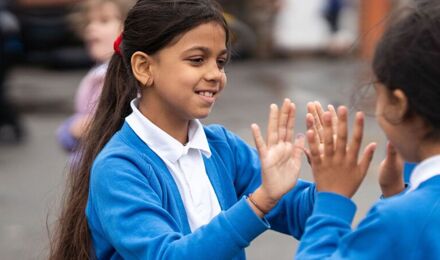 Two girls playing clapping games in the playground