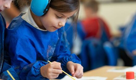 Two girls, one wearing ear defenders, painting